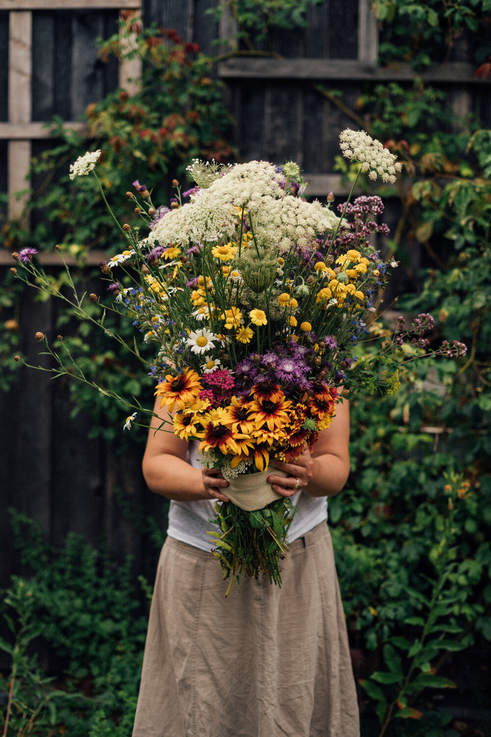 Vrouw met een groot zelfgemaakt boeket wilde bloemen