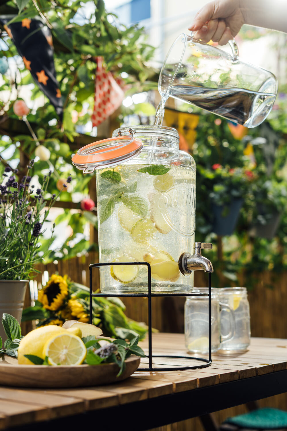Water in een drankdispenser met citroen en munt, zelfgemaakte limonade op het balkon