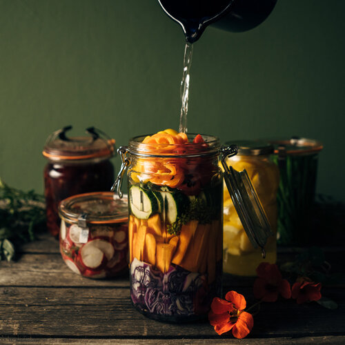 Groenten om te fermenteren: wortel, courgette en rode kool in een beugelpot, overgoten met pekel